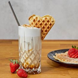 Das Bild zeigt ein Glas mit Eiskaffee, verziehrt mit einem Waffelherz am Rand.