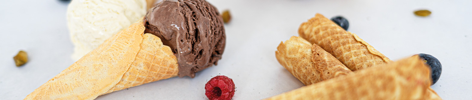 Das Bild zeigt gerollte Eiserkuchen mit Eis und Beeren.