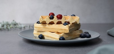 Das Bild zeigt auf einem Teller gestapelte belgische Waffeln mit Beeren. 