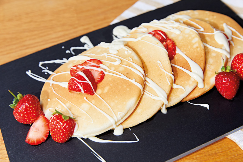 Das Bild zeigt Pancakes mit Erdbeeren. 